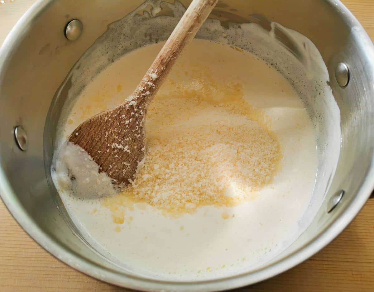 making parmigiano cream with butter, cream and grated parmigiano in saucepan