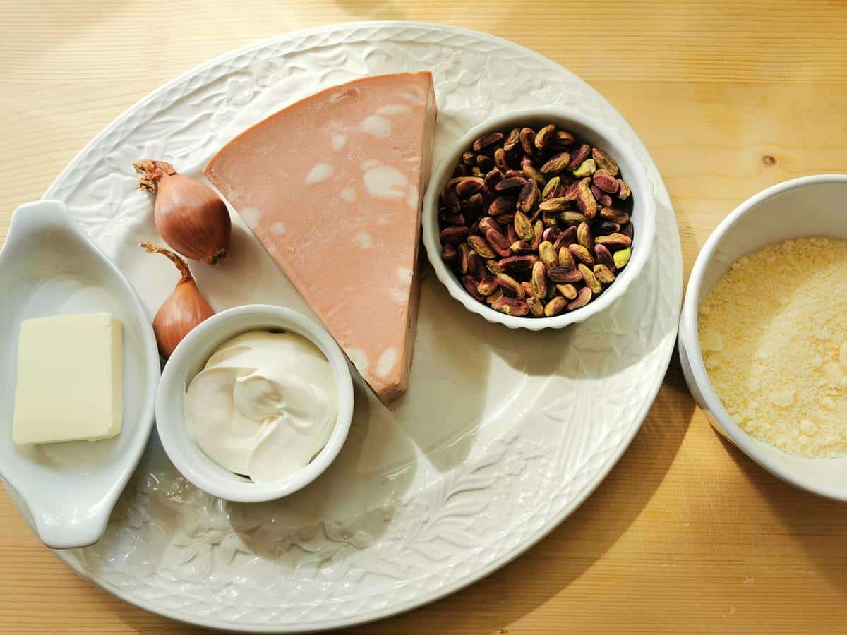 Ingredients for pasta with mortadella and pistachios on white plate.