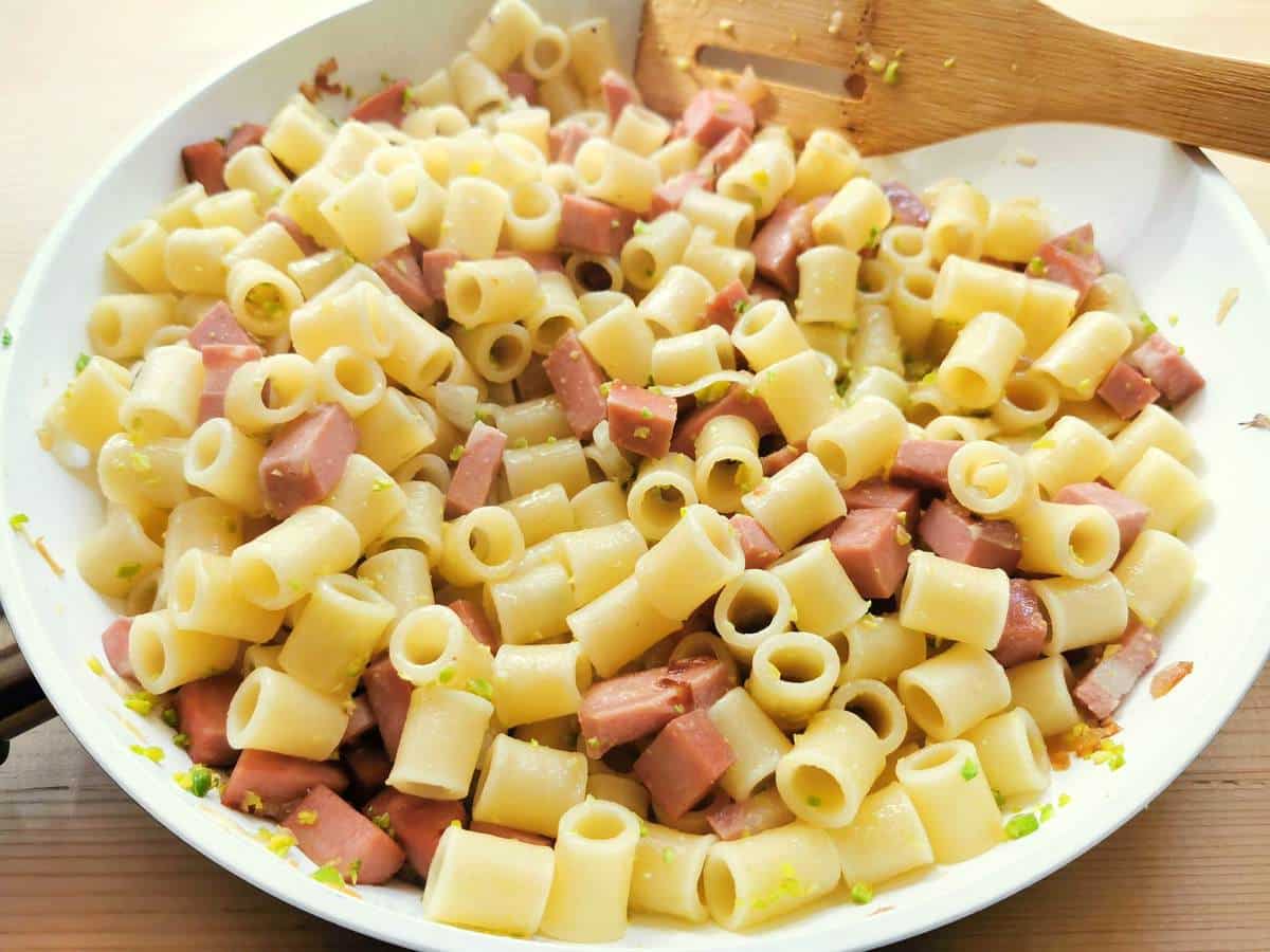 pasta, mortadella and pistachios mixed together in pan