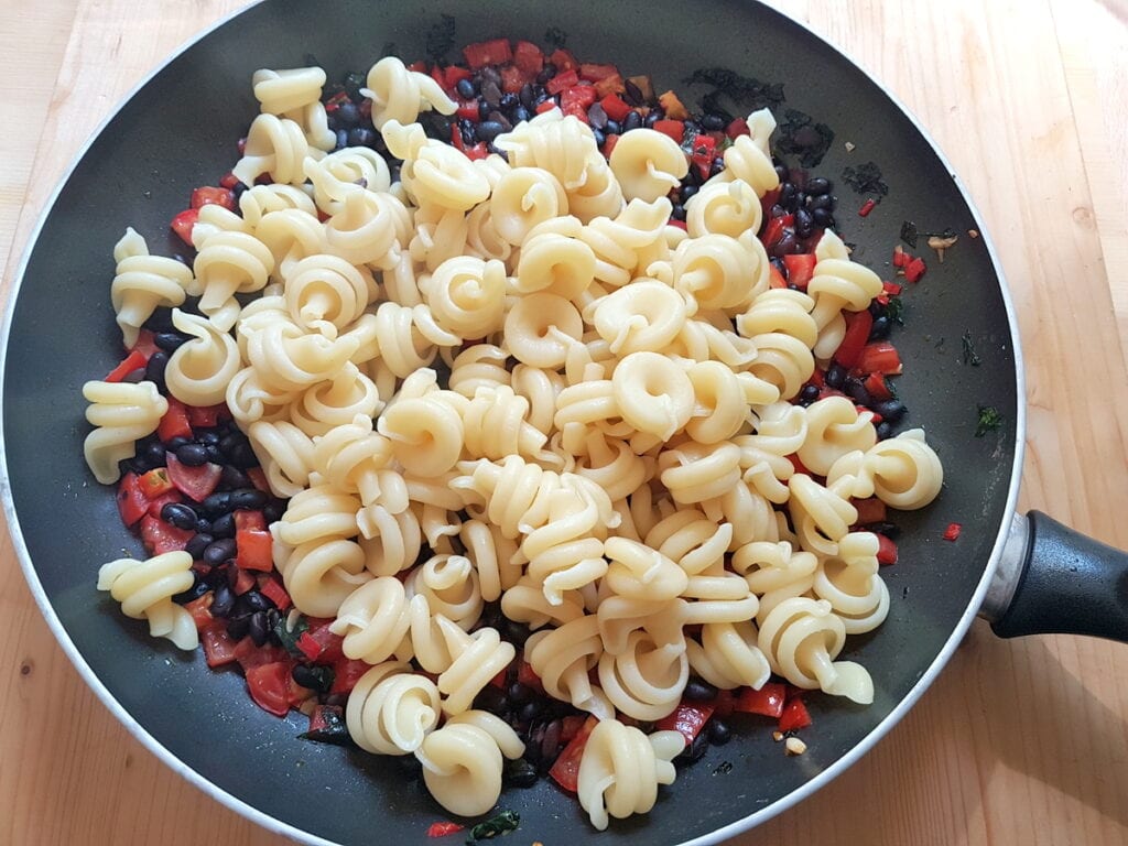 cooked pasta in skillet with beans and tomatoes