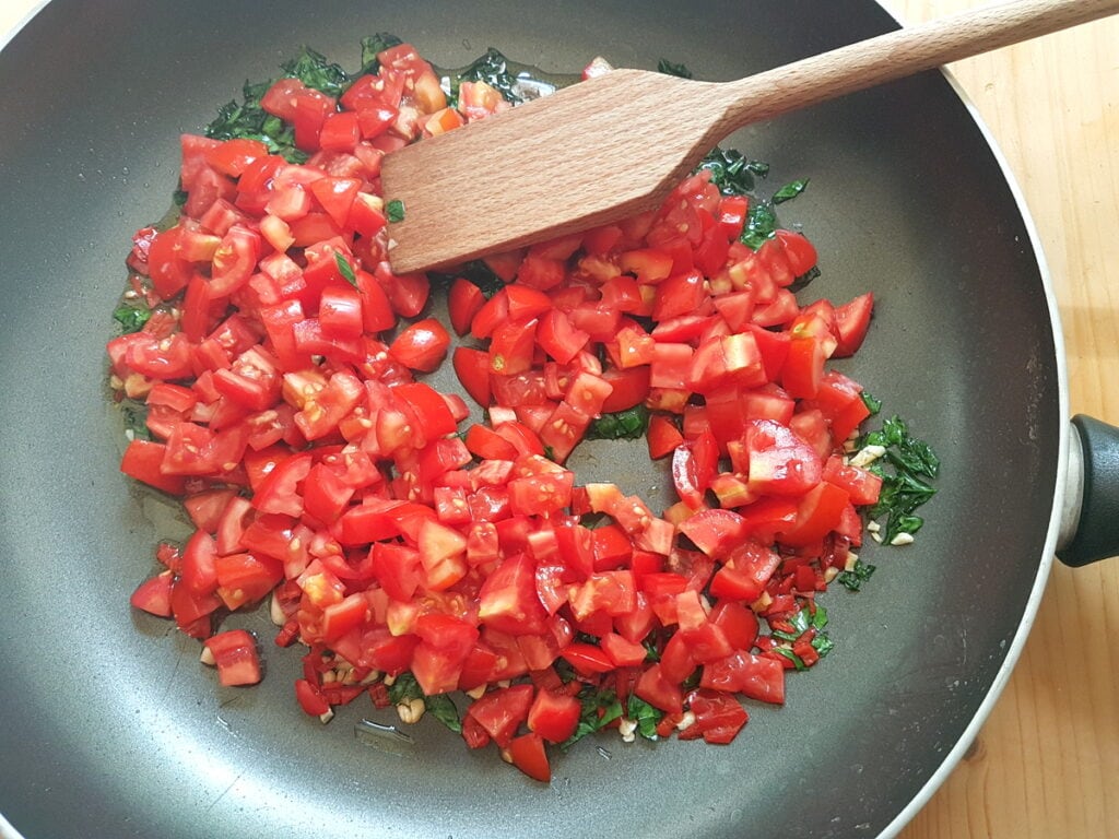 chopped tomatoes in skillet with garlic, parsley and peperoncino