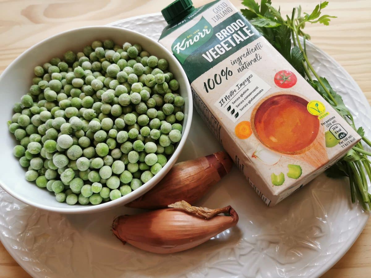 Ingredients for pasta with peas; shallots, a bowl of peas, fresh parsley and vegetable broth.