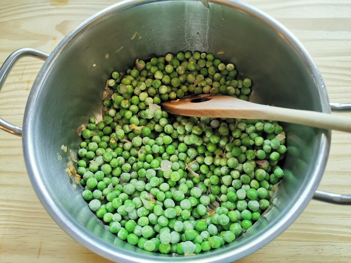 Peas added to onions and olive oil in pan.