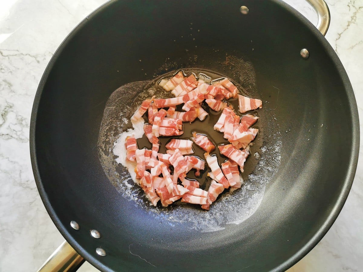 Pancetta frying in a pan.