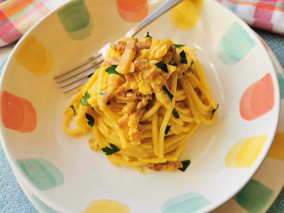 Saffron pasta served in a bowl with a fork.