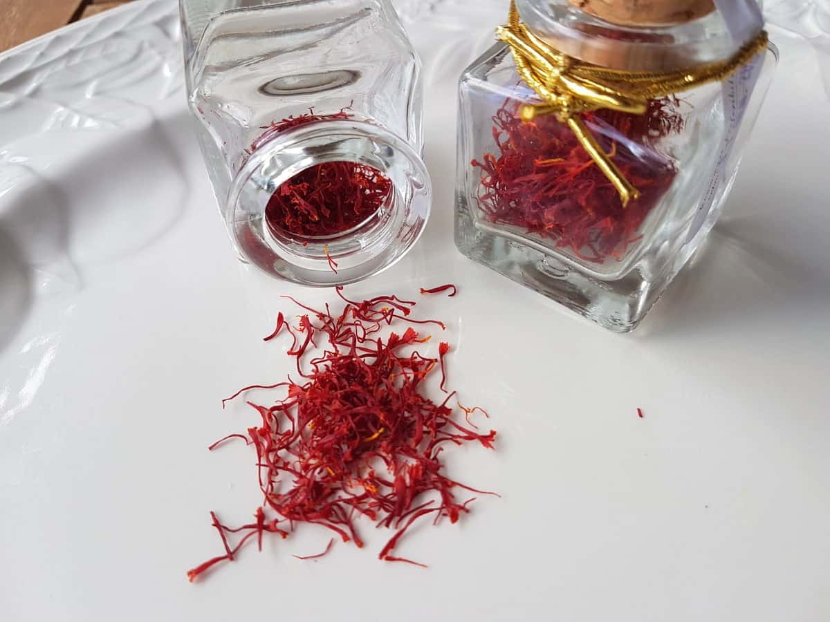 dried saffron threads from Abruzzo in glass jar and on white plate