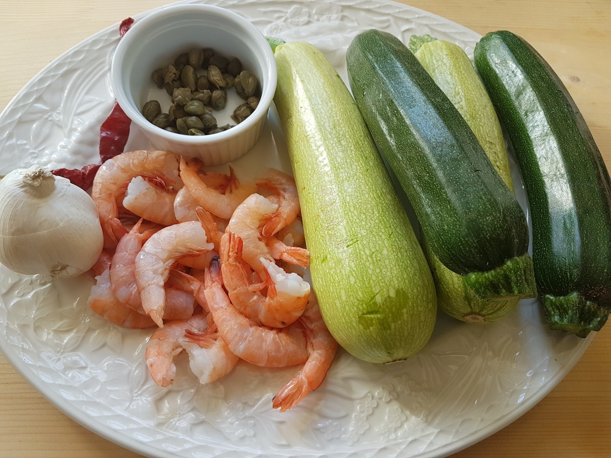 Courgettes, prawns.  capers, garlic and chili peppers on a kitchen table.