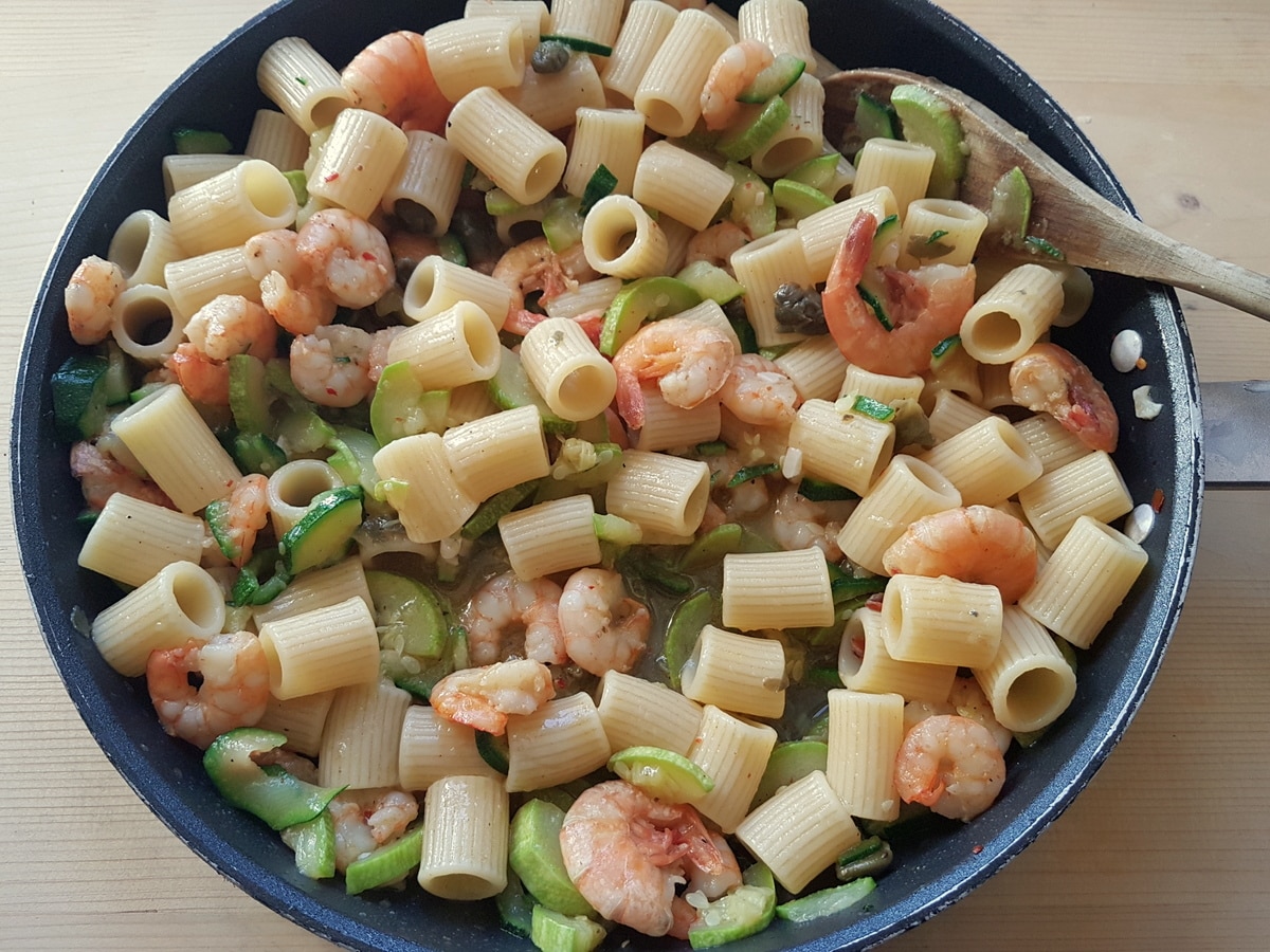 Pasta added to the pan with shrimp and courgettes.