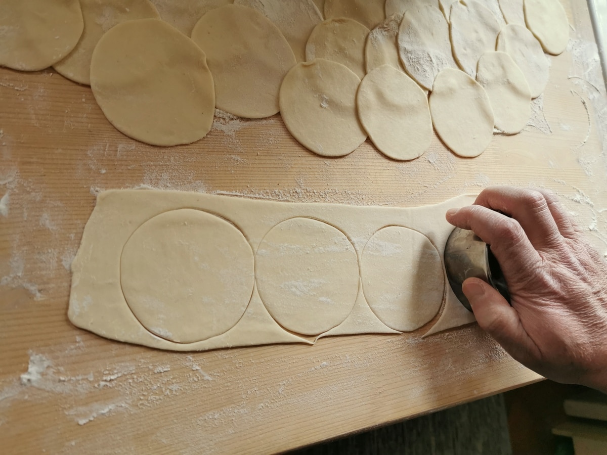 Ravioli dough being shaped on a board.