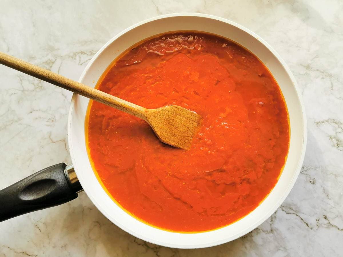 Tomato passata added to frying pan.