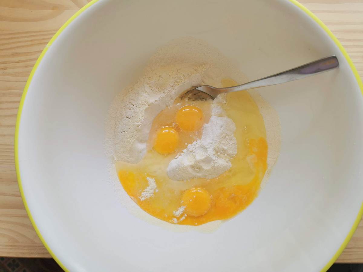 Flour in large bowl with 4 eggs broken into it.