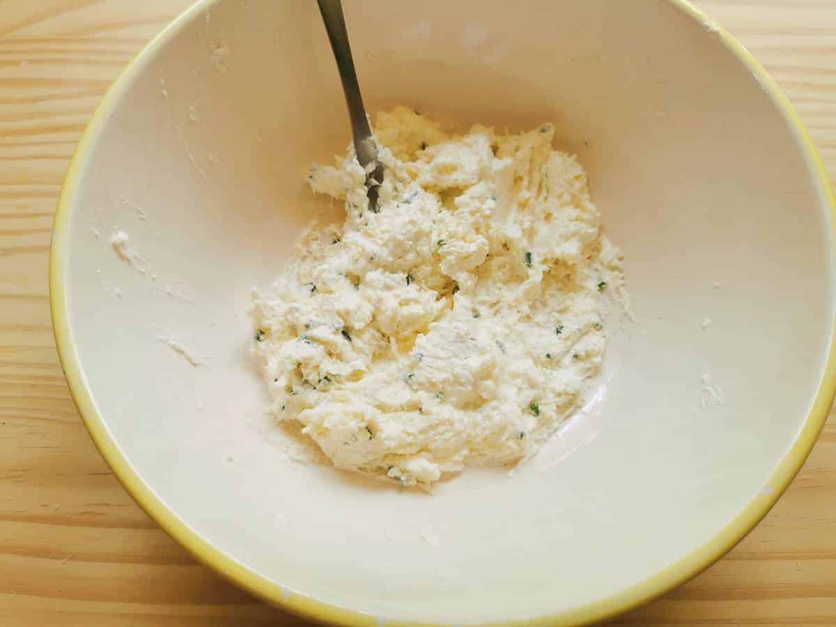 Ready mixed robiola cheese pasta filling in large bowl with a fork.
