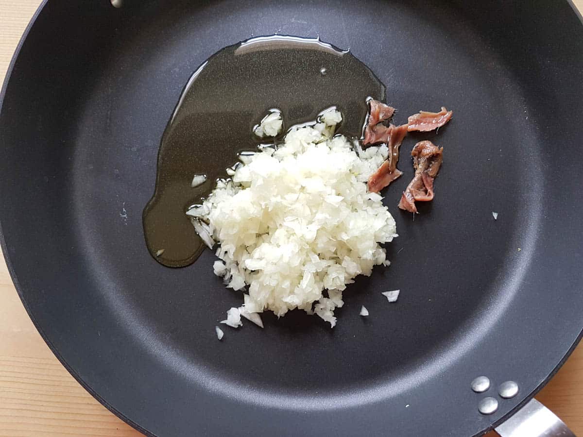 Chopped onion and anchovy fillets in a frying pan