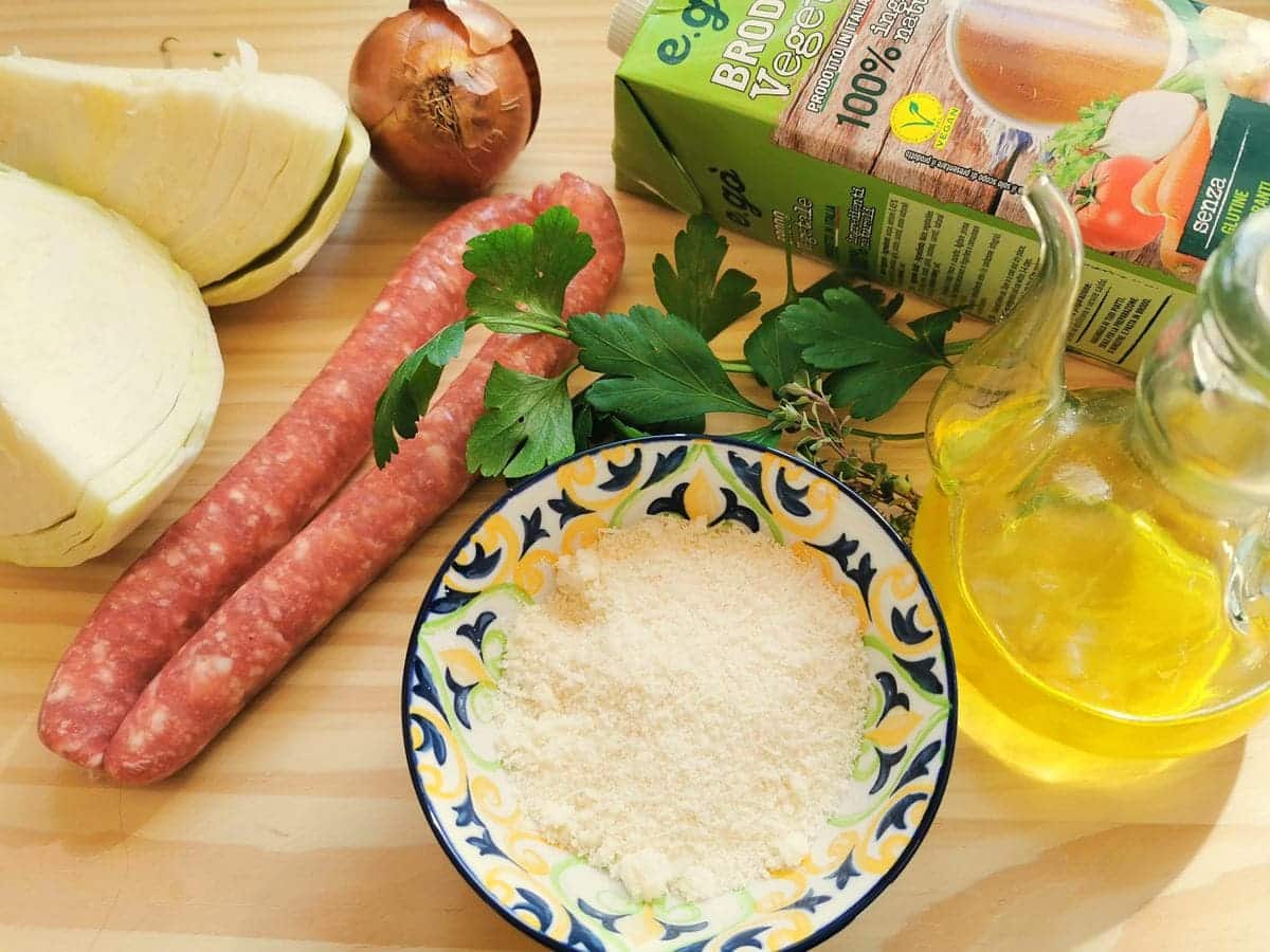 Ingredients for sausage and cabbage pasta on wood work surface.