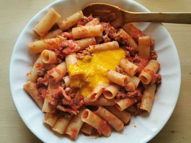 rigatoni and sauce in white bowl with added beaten egg yolks and pecorino