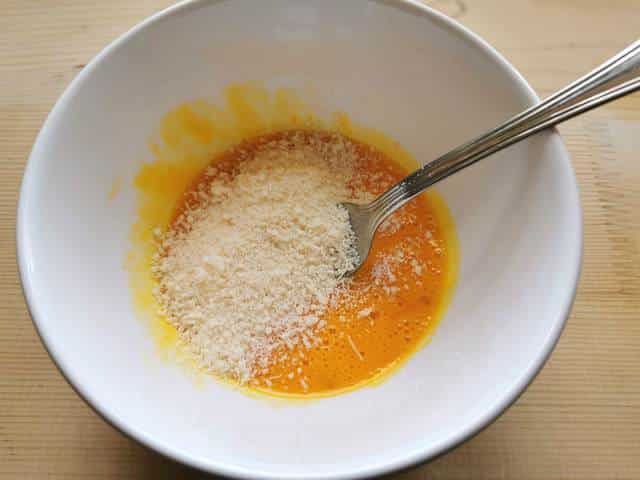 beaten egg yolks and grated pecorino in white bowl