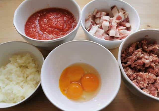 guanciale, sausage meat and onions chopped and prepared and egg yolks and passata all in white bowls