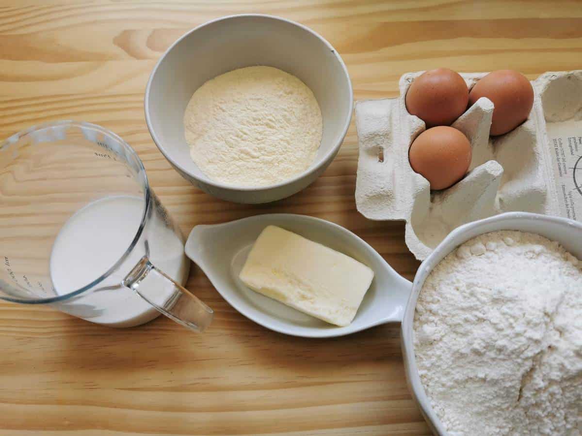 Ingredients for scarpinocc dough on wood work surface; flour, butter, milk and eggs.