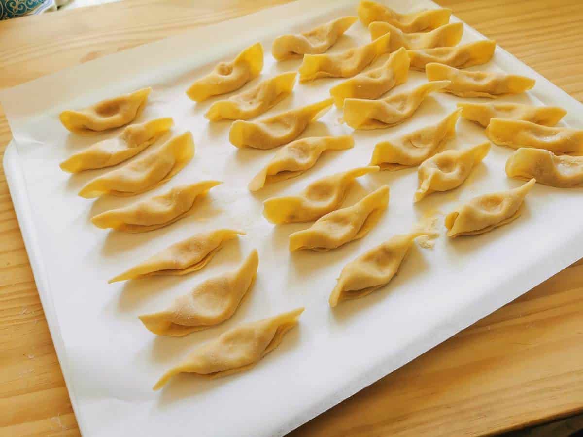 Ready uncooked scarpinocc on baking paper sheet on a tray.
