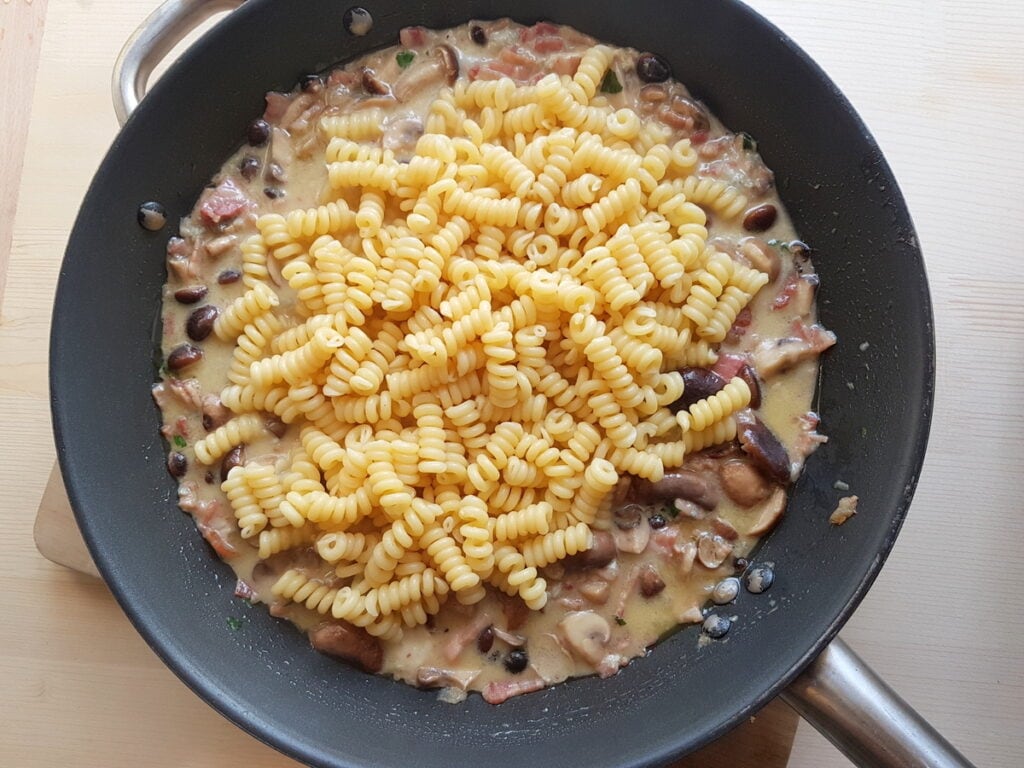 cooked short fusilli bucati added to the gorgonzola, pancetta and mushroom sauce in skillet