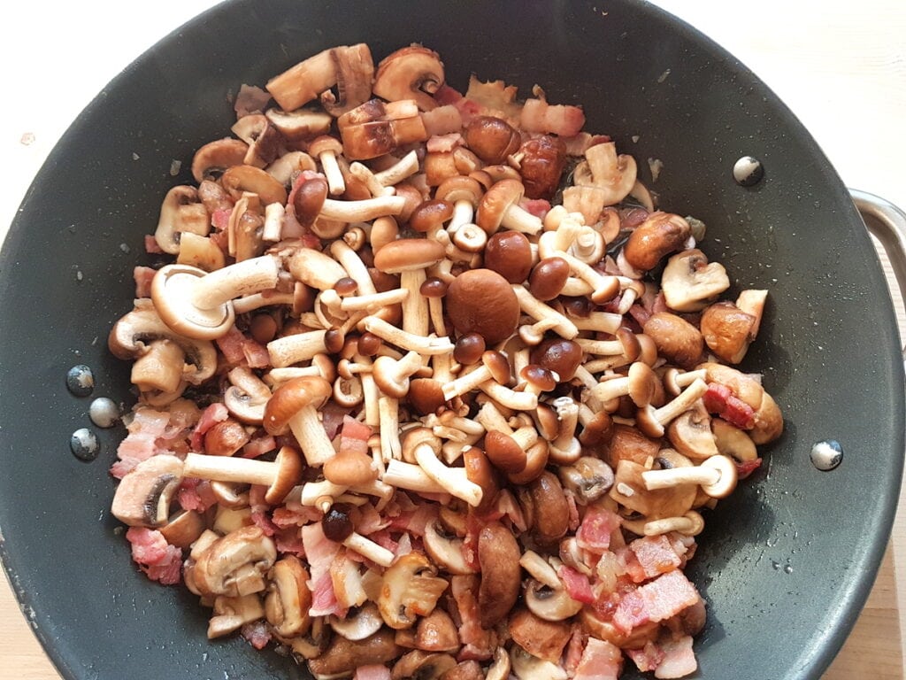 Cleaned and prepared mushrooms in skillet with onion and pancetta