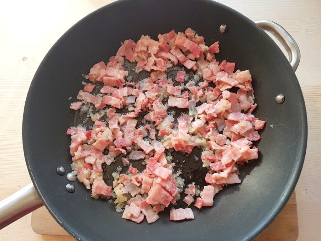 chopped onion and cubed pancetta cooking in skillet