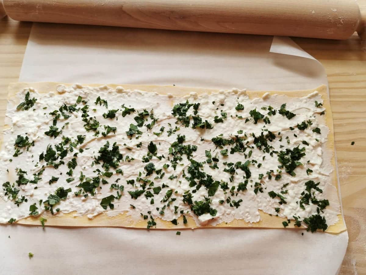 Fresh  chopped parsley sprinkled on stracchino cheese covered pasta sheet.