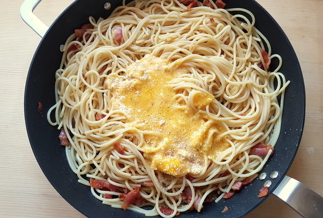 spaghetti, guanciale, eggs and grated cheese in frying pan for spaghetti alla carbonara 