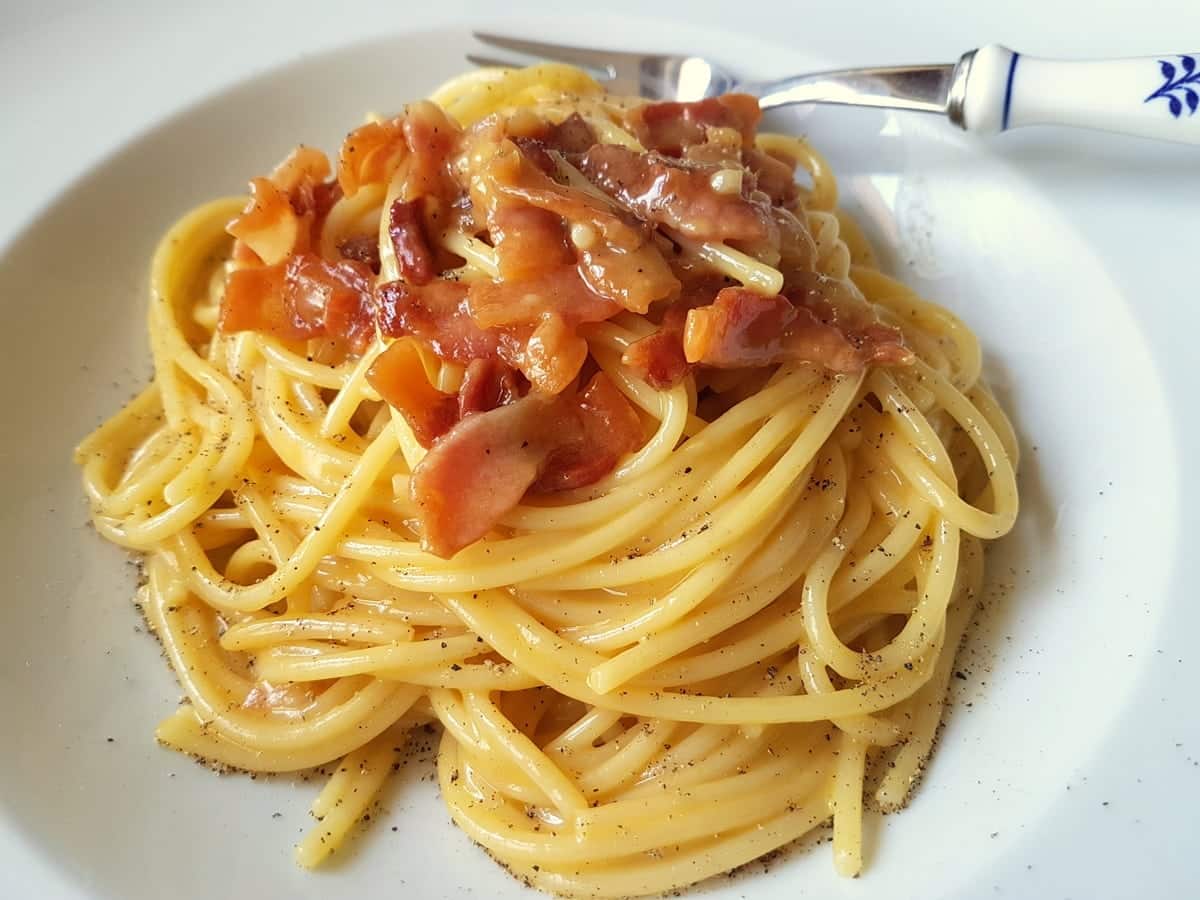 Spaghetti carbonara on a plate with additional black pepper