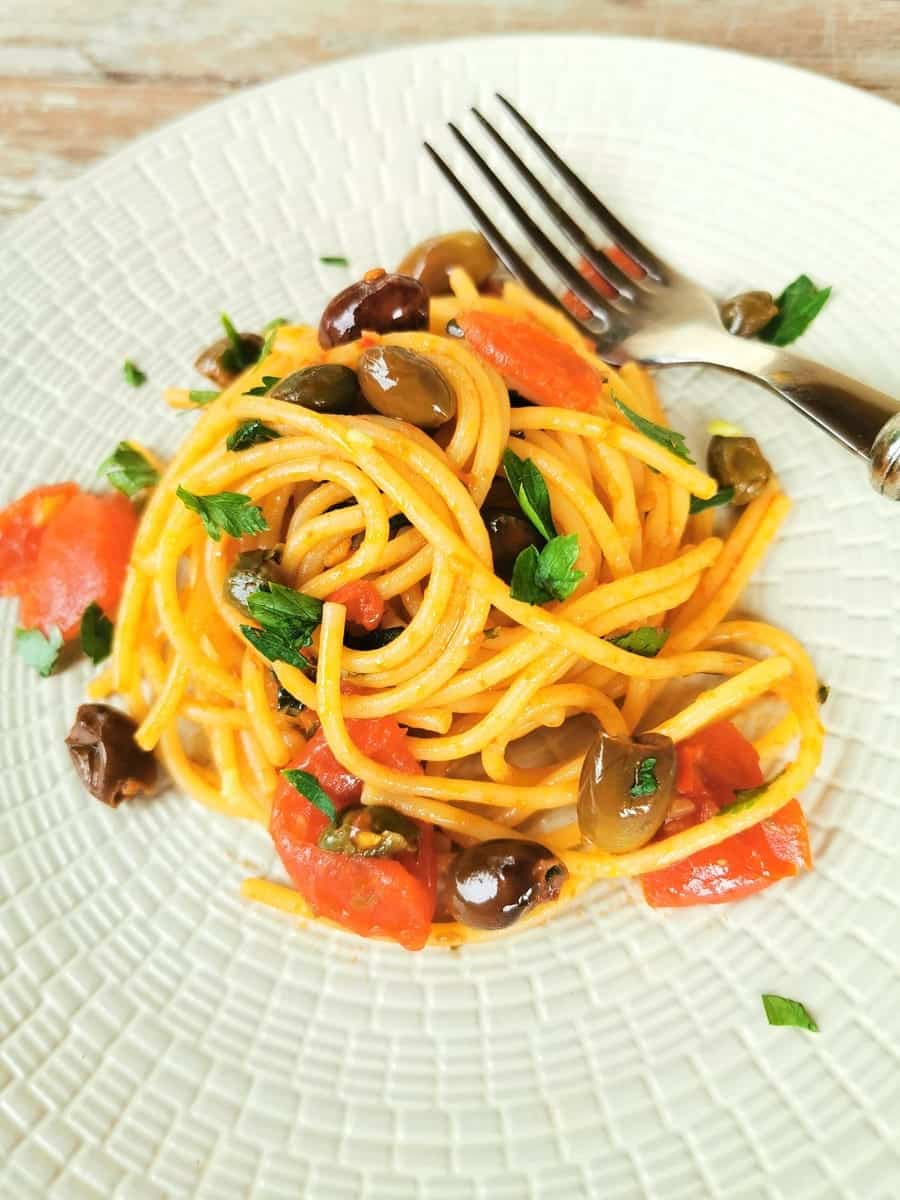 Spaghetti alla puttanesca served on a kitchen table.