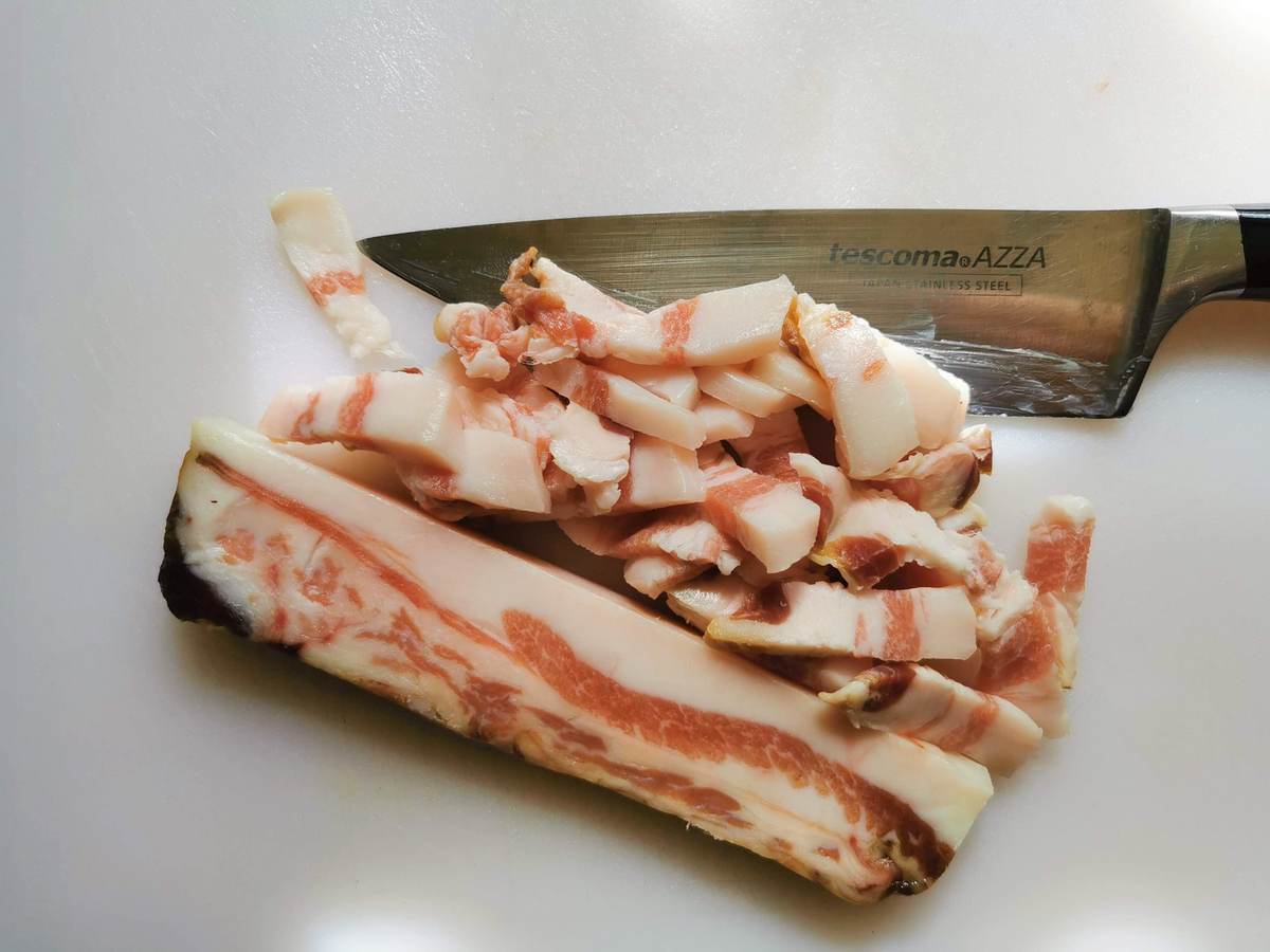 Guanciale that has been sliced on a chopping board.