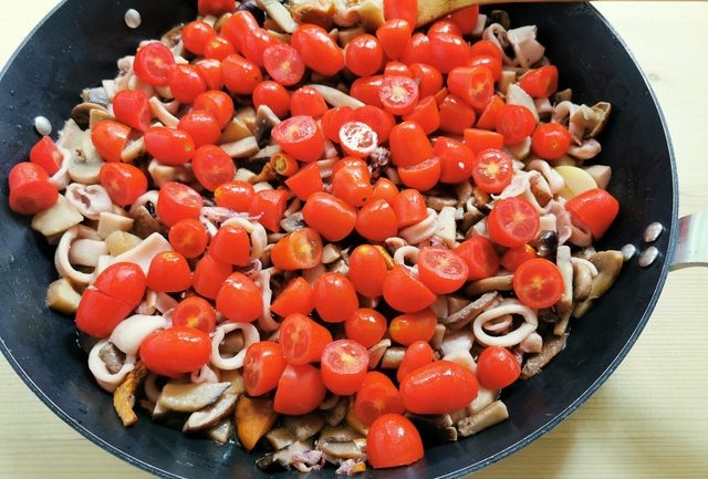 mushrooms, calamari and tomatoes cooking in skillet