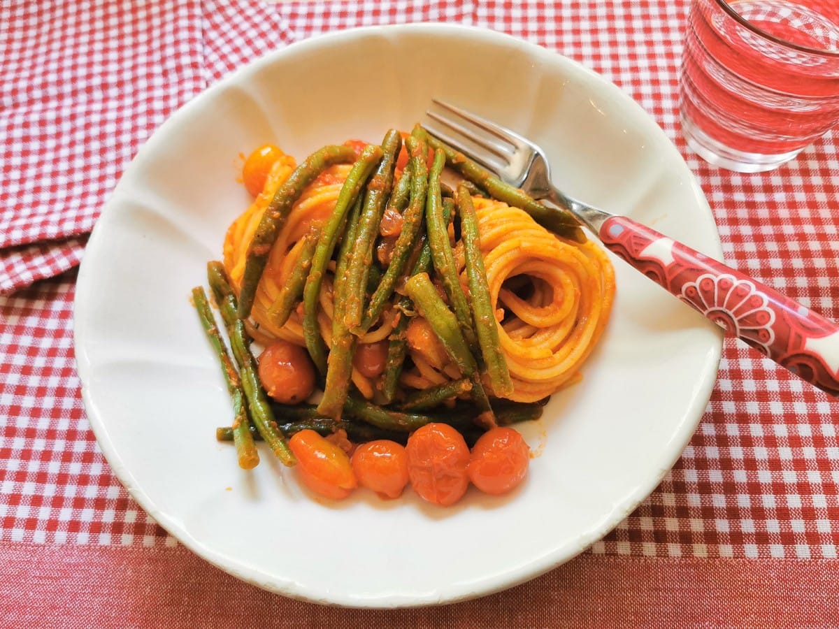 Spaghetti with green beans in a white bowl.