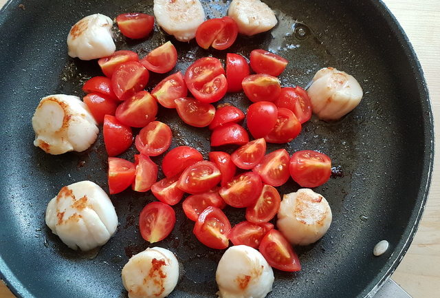 scallops and cherry tomatoes cooking in frying pan