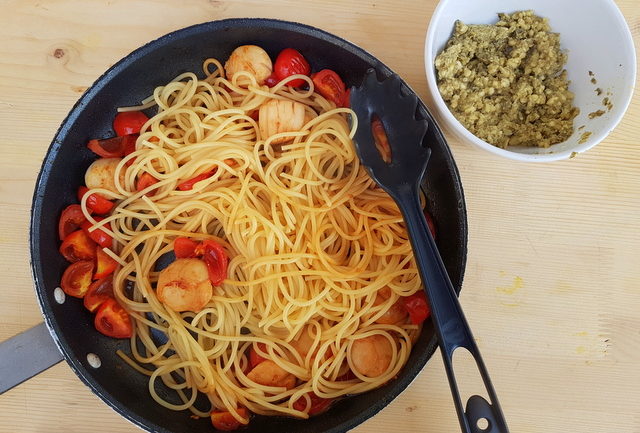 spaghetti, scallops and tomatoes in frying pan with almon, caper, citrus fruit pesto