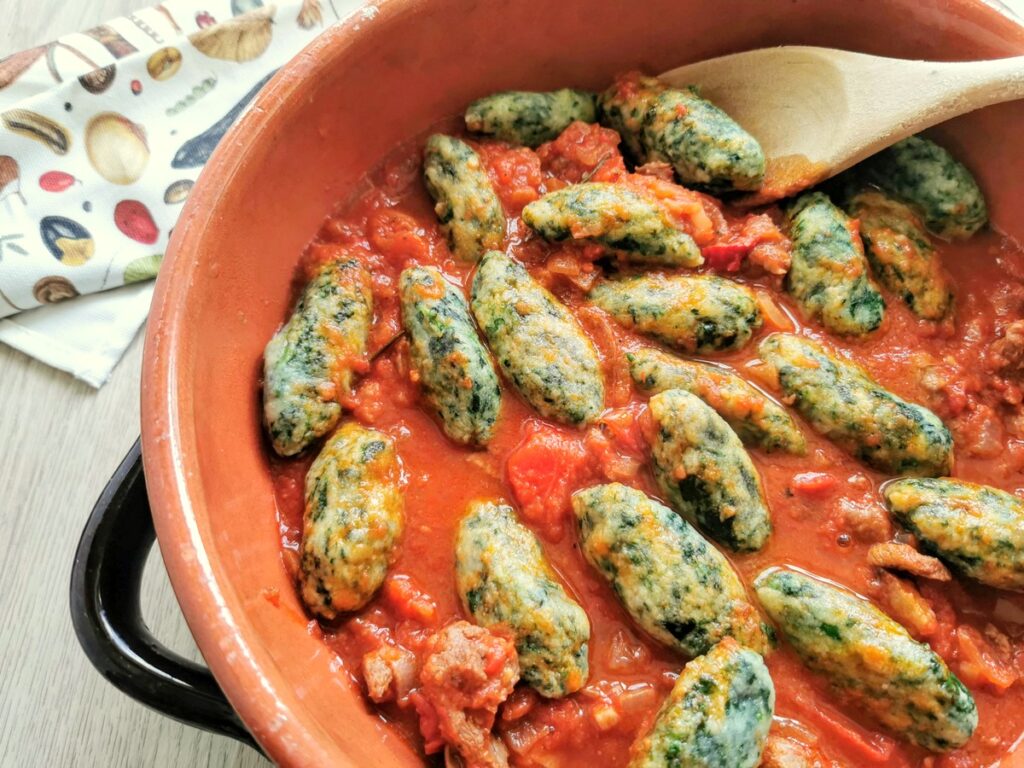 cooked  spinach gnocchi in serving bowl with lamb ragu