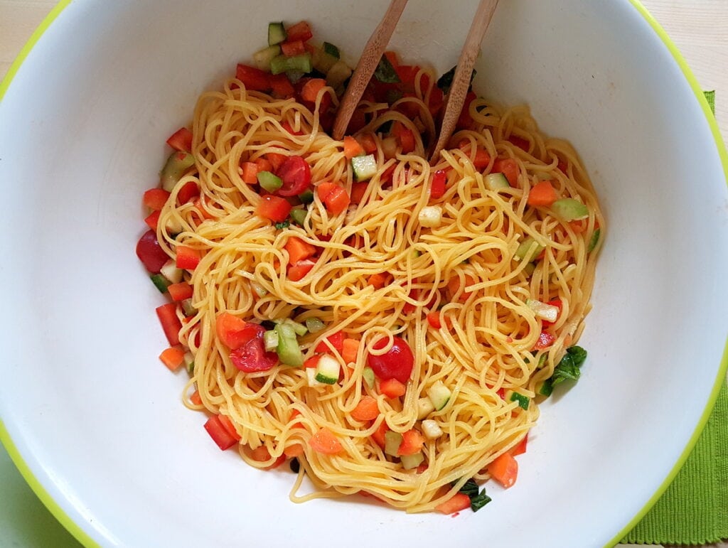 tagliolini and marinated vegetables mixed together in bowl