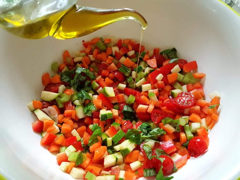 chopped vegetables in bowl with olive oil and lemon juice.