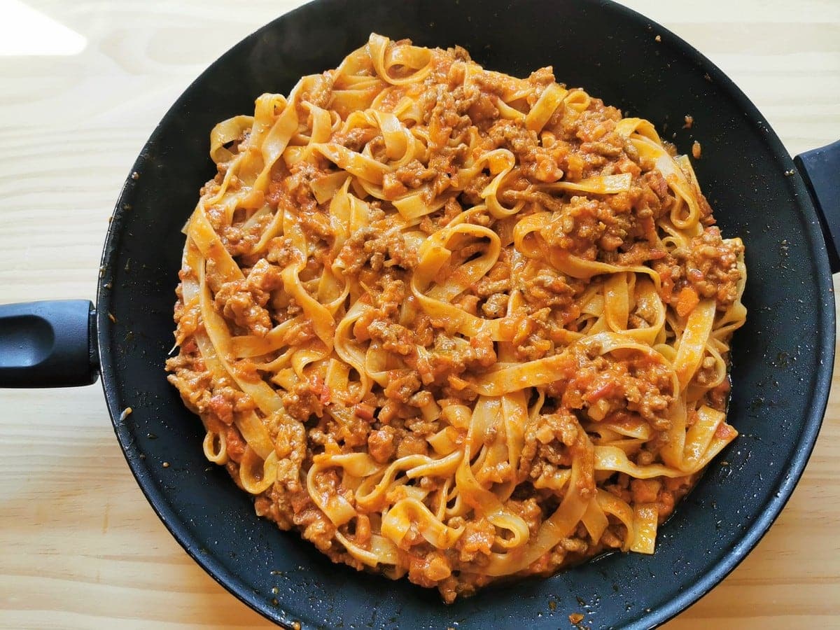 Tagliatelle bolognese in a frying pan.