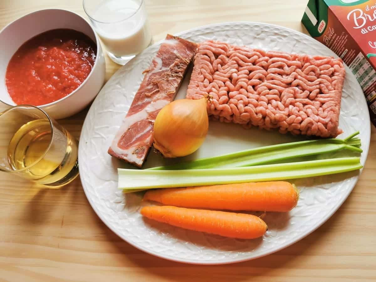 Ingredients for bolognese sauce on wood worktop.