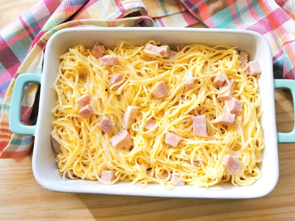 tagliolini with ham and cream sauce in rectangular oven dish.