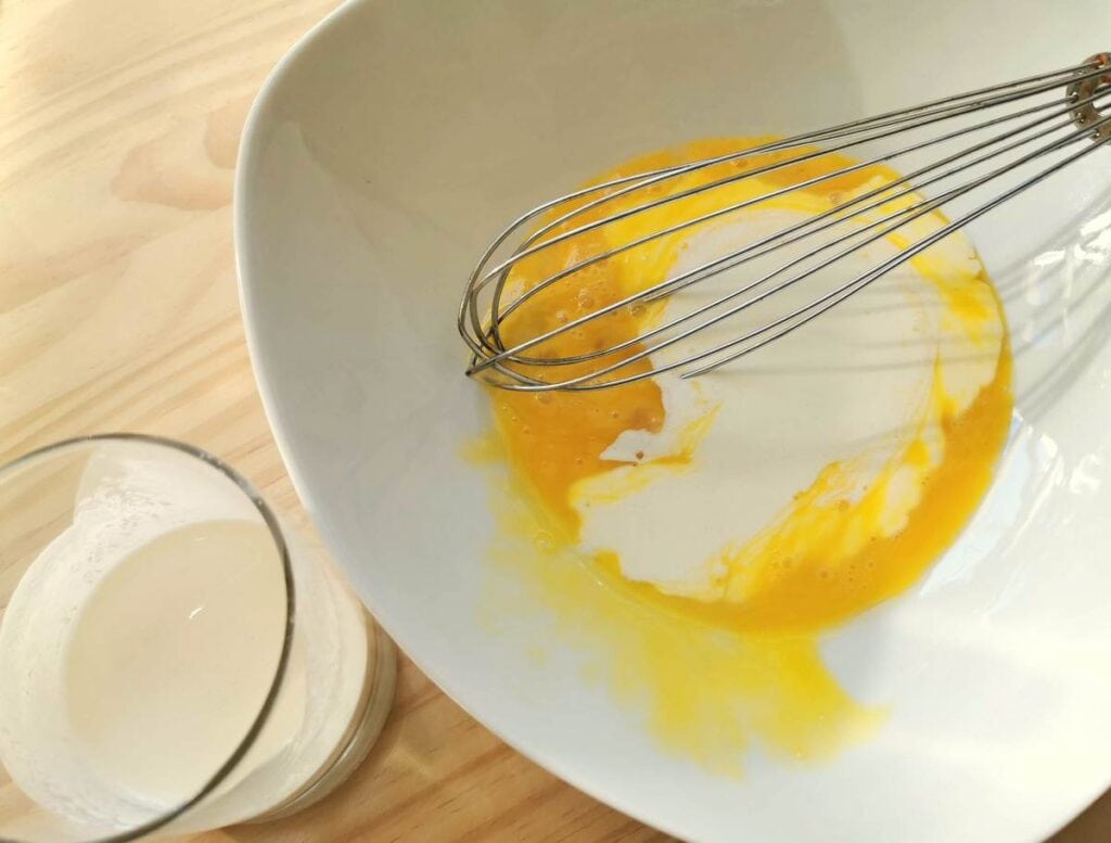 beaten egg yolks and cream in white bowl