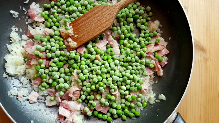 peas, onions and pancetta cooking in frying pan