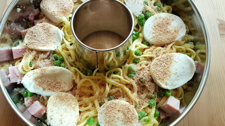 mozzarella slices on top of pasta layer in ring cake tin 