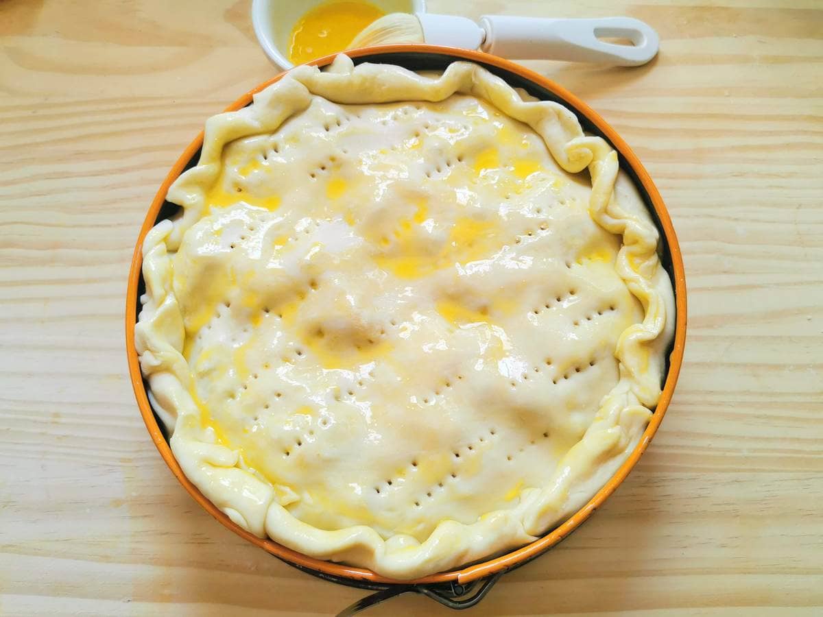 uncooked tortellini Bolognese pasticcio pie bruched with egg yolk and pricked with a fork to make holes.