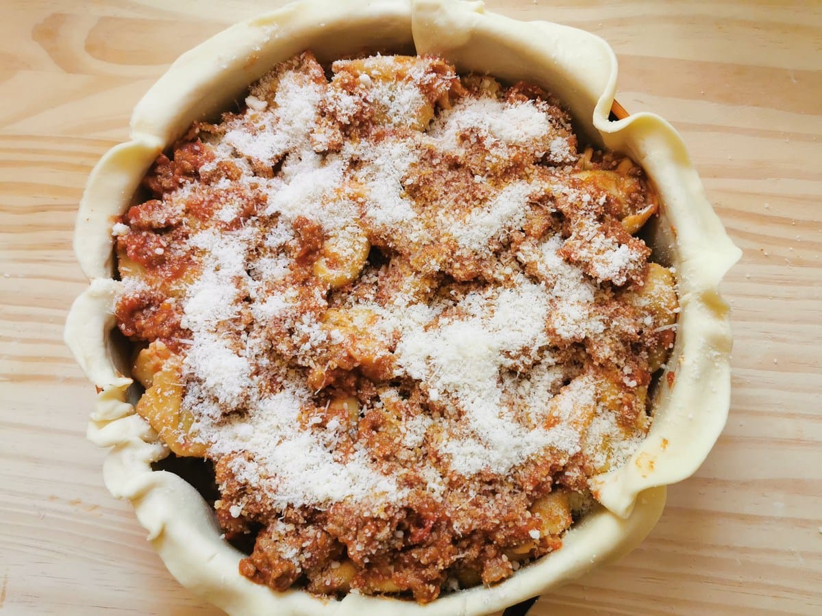 the final layer of Bolognese sauce and grated Parmigiano in cake tin.