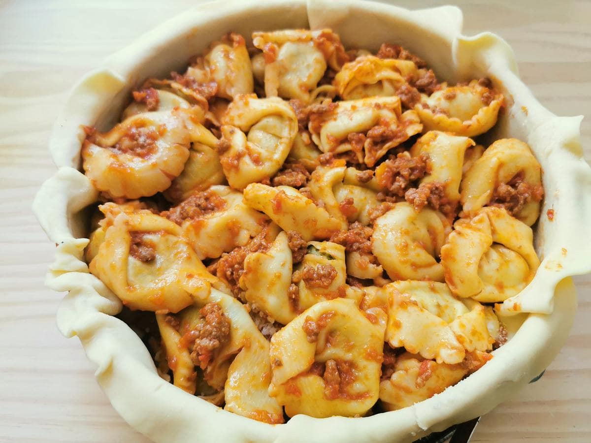 A second layer of tortellini with Bolognese in cake tin.