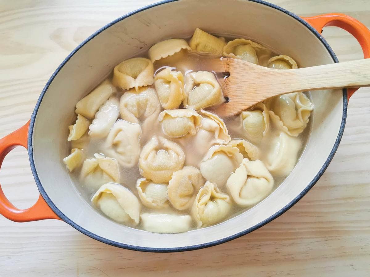 fresh tortellini cooking in beef broth in Dutch oven