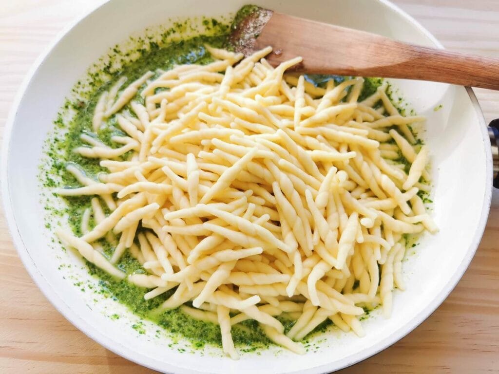 cooked trofie pasta in frying pan with rocket pesto