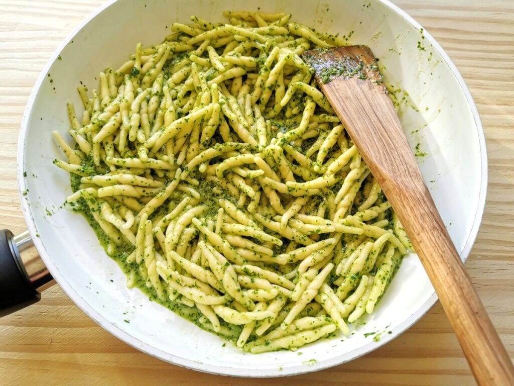 trofie pasta mixed with rocket pesto in frying pan